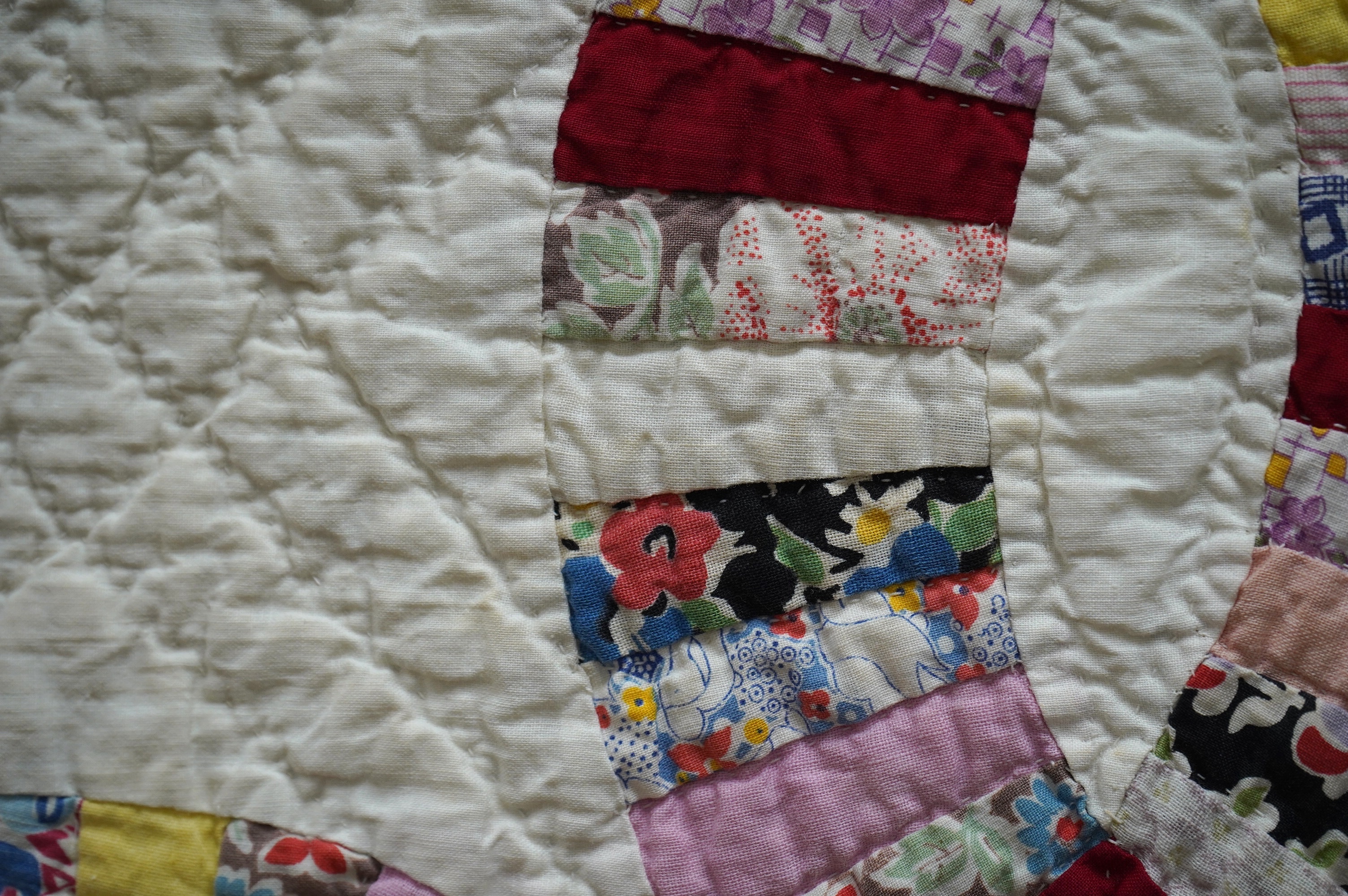 A 1940’s hand made ‘Double Wedding Ring’ patchwork quilt, made from bright multi-coloured floral and plain cotton dress fabrics into a patchwork design of large all over interlocking rings with a scalloped bright yellow